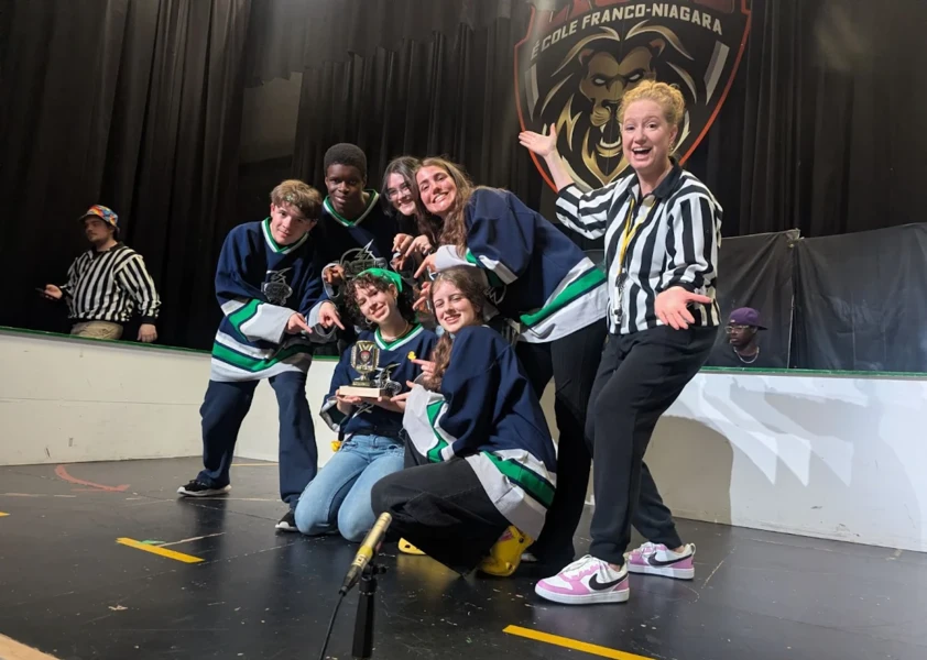 Équipe d’improvisation d’élèves posant avec leur trophée sur scène après une victoire lors d’un tournoi.