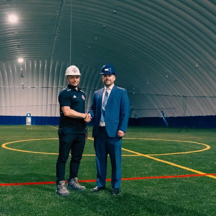 Pavel Cancura, directeur général du Ottawa TFC Soccer Club et Marc Bertrand se serrent la main sur le terrain intérieur du dôme sportif.
